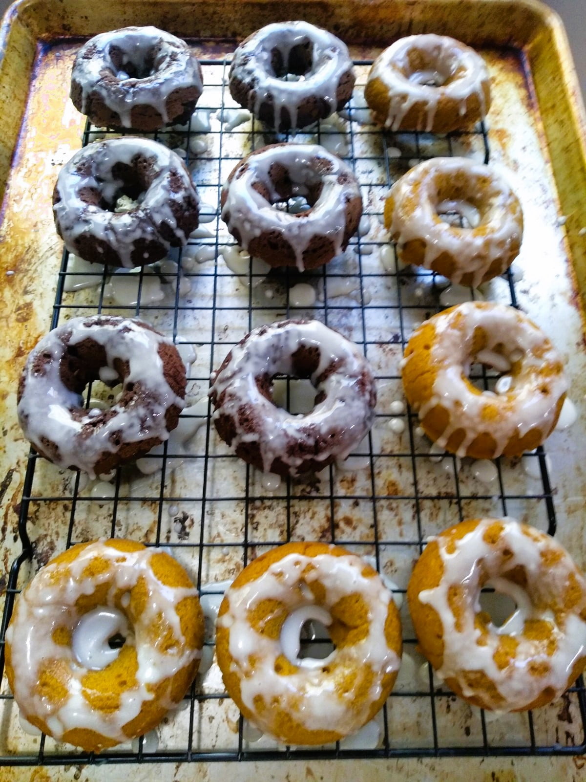 a dozen iced doughnuts on cooling rack
