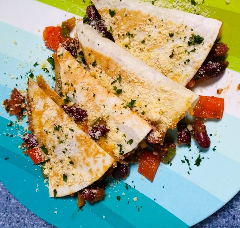 4 triangle quesadilla slices overlapping on blue and green plate
