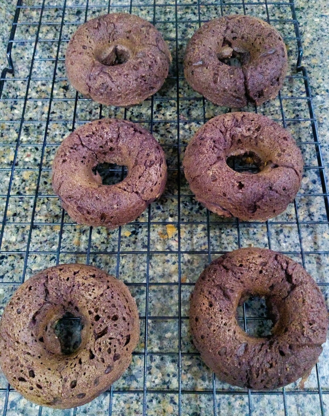 fresh baked chocolate doughnuts on the cooling rack